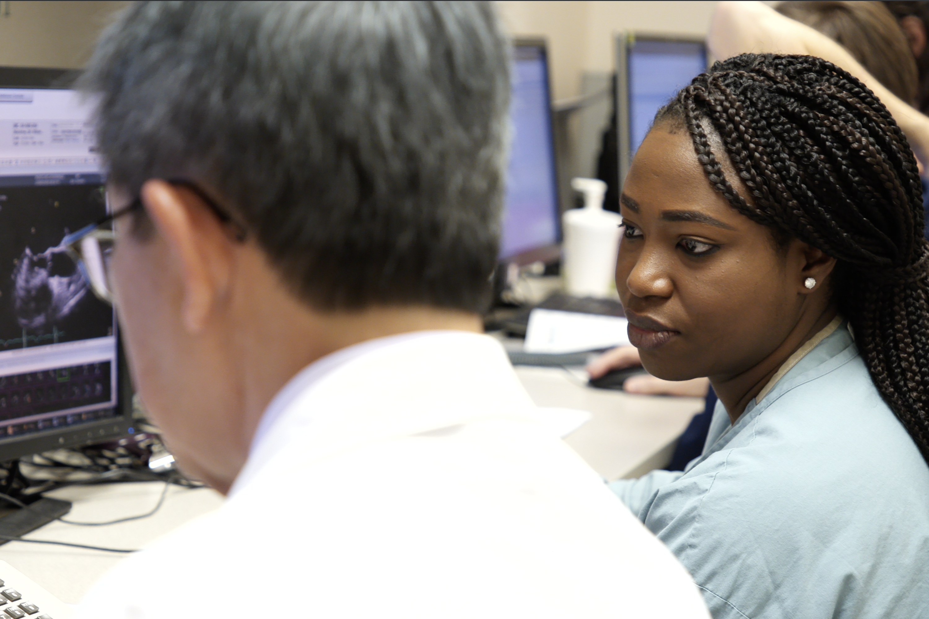 Two healthcare professionals reviewing a cardiac ultrasound image on a clinical workstation monitor.
