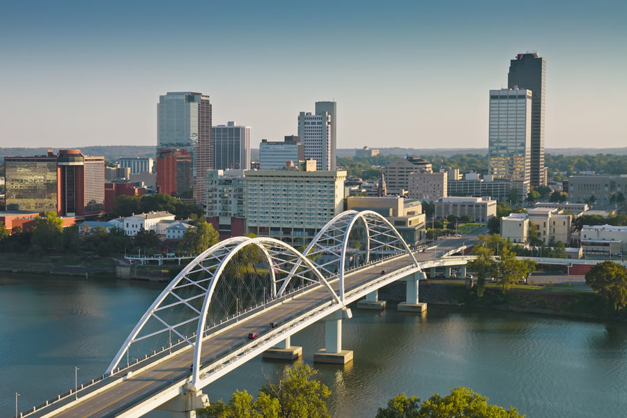 Little Rock, Arkansas skyline with the Broadway Bridge's white arches spanning the Arkansas River in the foreground.