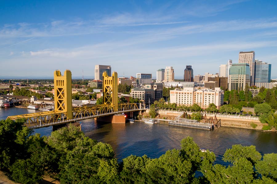 Sacramento, California skyline along the Sacramento River, with the iconic gold Tower Bridge in the foreground on a clear summer day