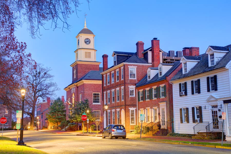 Historic downtown Dover, Delaware street scene at dusk featuring colonial brick buildings and a clock tower.