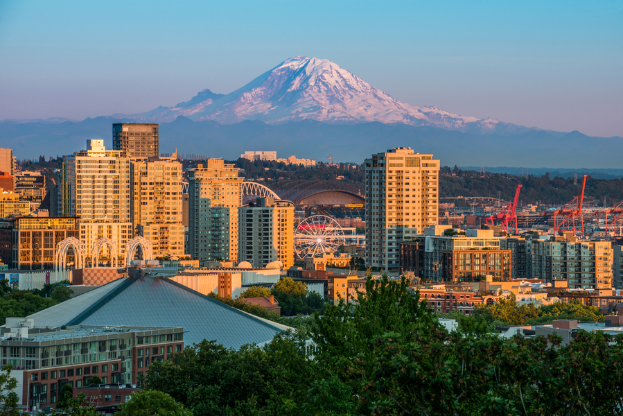 Seattle, Washington skyline at golden hour with the Great Wheel ferris wheel, T-Mobile Park, and snow-capped Mount Rainier in the background.