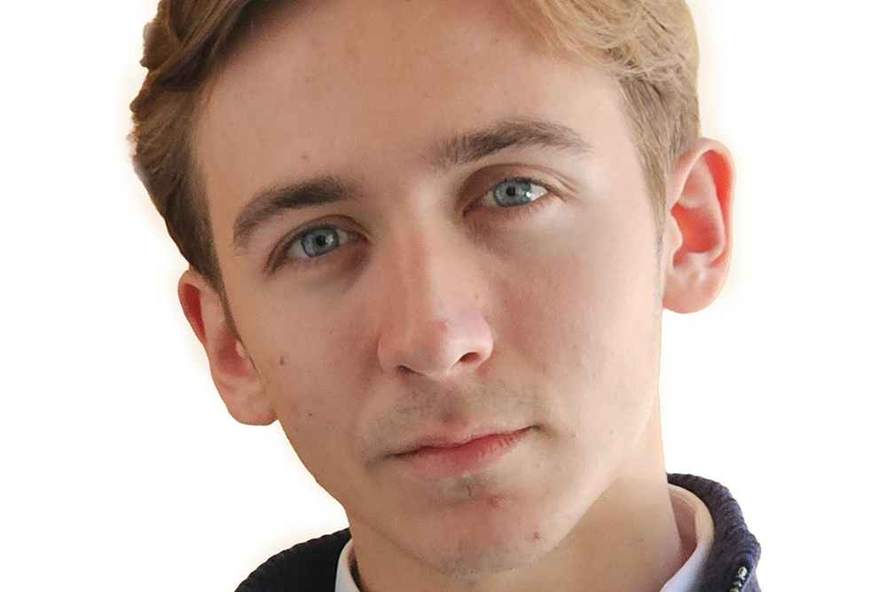 Headshot of a young man in a navy zip-up sweater against a plain white background.