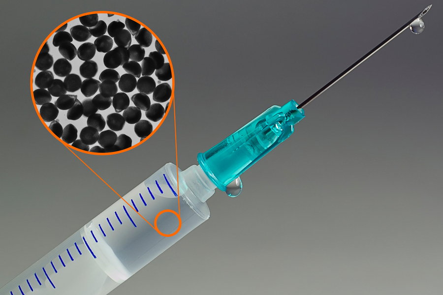 Syringe needle with an inset showing a close-up of small spherical particles.