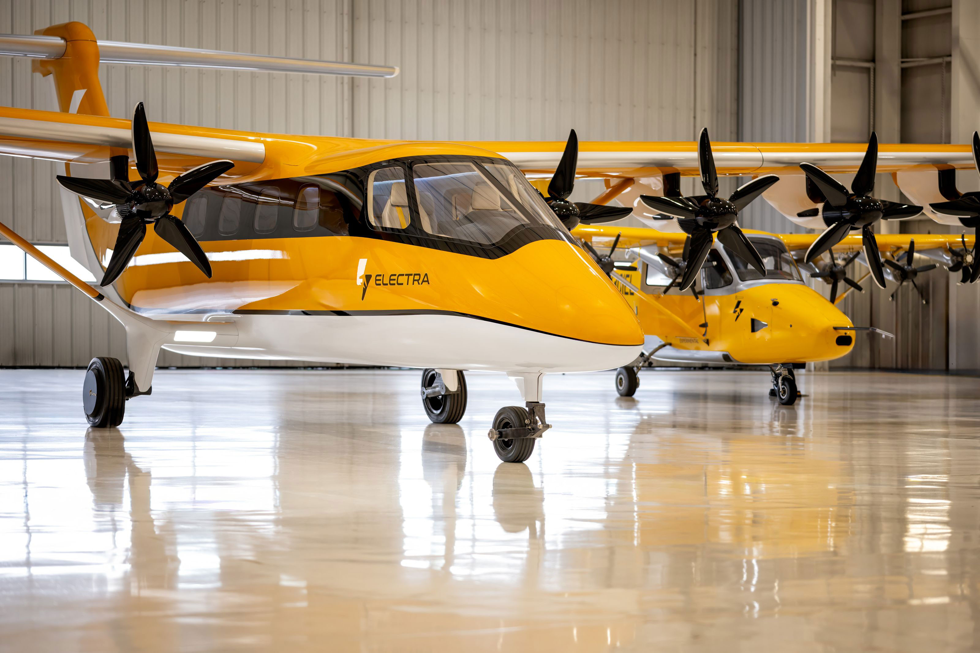 Yellow Electra aircraft parked inside a hangar, with a second aircraft behind it.