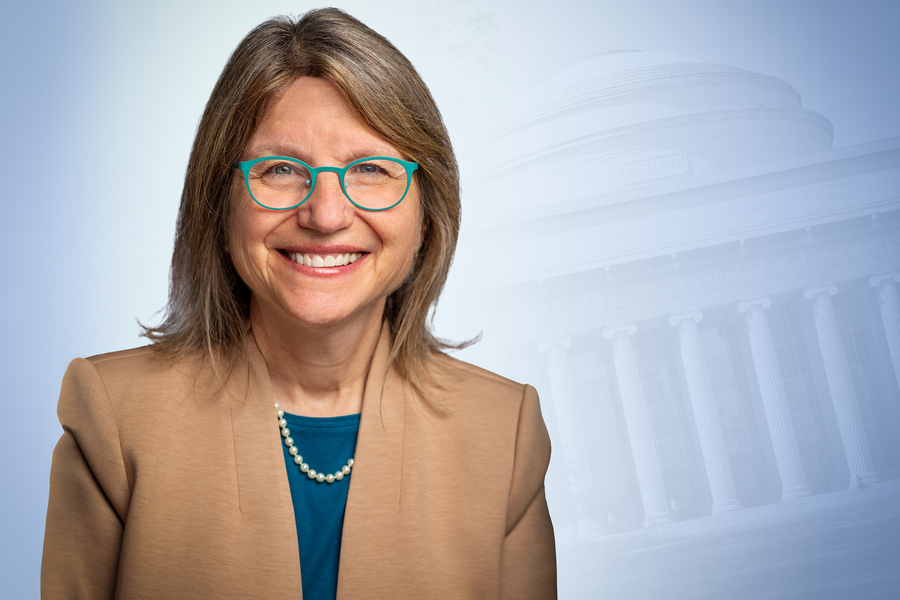 Headshot of MIT president Sally Kornbluth in a tan blazer and teal glasses smiling warmly, with a faint illustration of the MIT dome visible in the background.