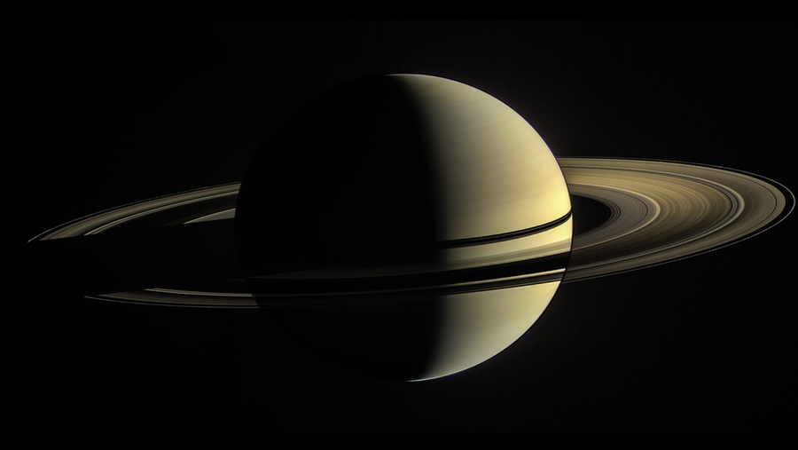Saturn with prominent rings shown in three-quarter view against black space background.