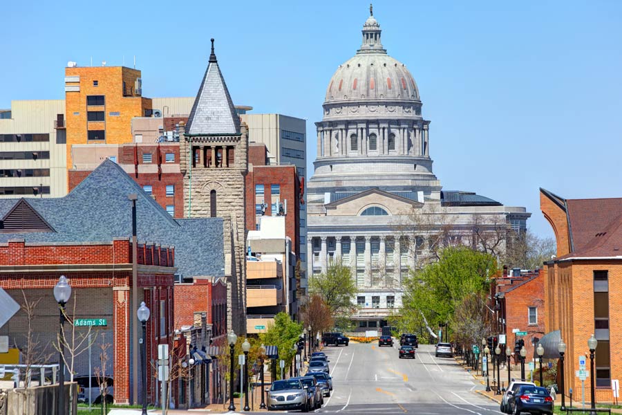 Street view of downtown Jefferson City, Missouri leading toward the Missouri State Capitol building dome on a clear spring day.