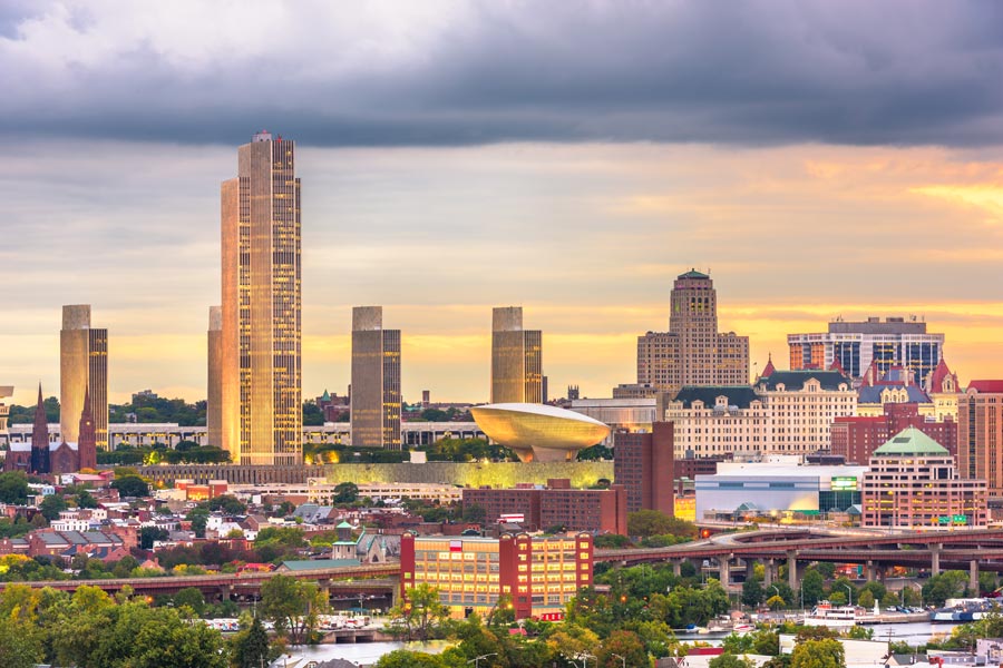 Albany, New York skyline at sunset featuring the Empire State Plaza's modernist towers and the distinctive egg-shaped performing arts center.