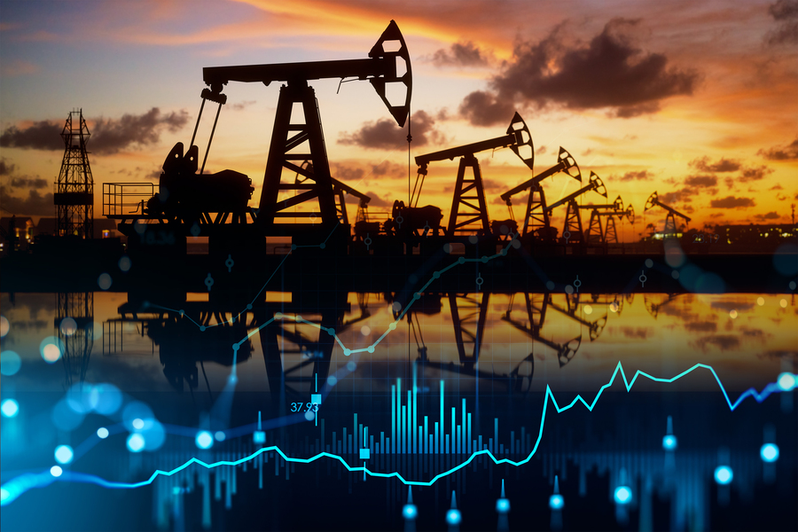 Composite image of silhouetted oil pump jacks at sunset reflected in water, overlaid with glowing blue financial data charts and trend lines.