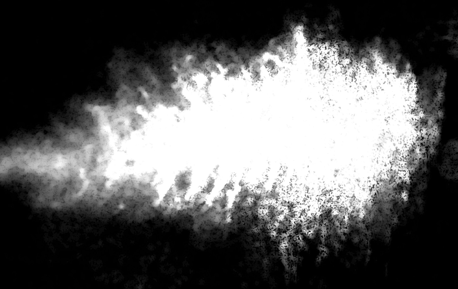 High-contrast black and white scientific image of a bright white diffuse plume or particle cloud expanding against a black background, representing nanoscale material behavior research.