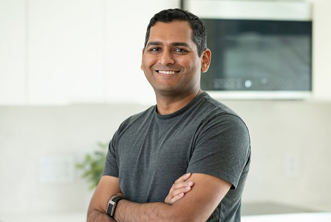 Adult standing indoors with arms crossed, wearing a short-sleeve shirt.